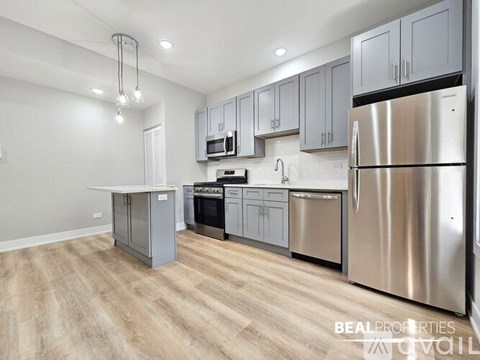 A modern kitchen with a stainless steel refrigerator and wooden flooring.