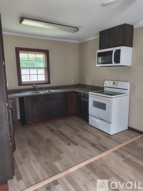 A kitchen with a white oven and wooden floors.