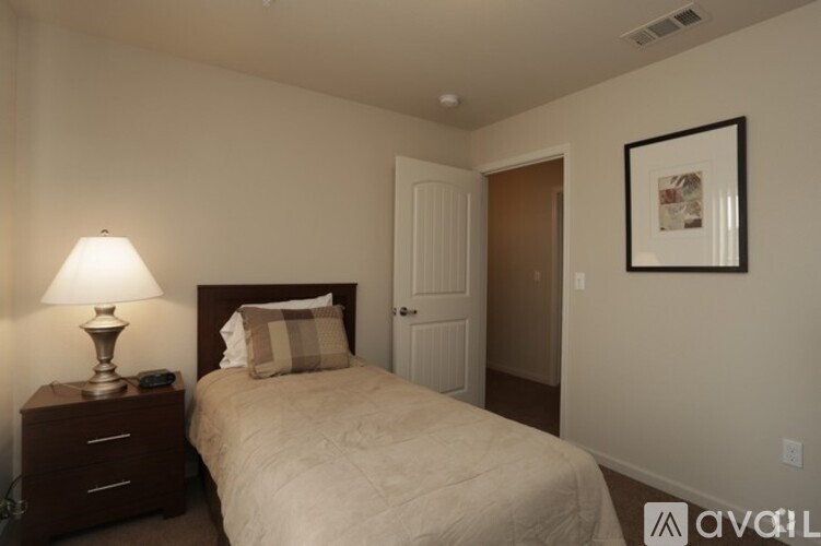 A bedroom with a bed, nightstand, and lamp.