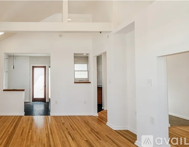 A spacious room with wooden floors and white walls.
