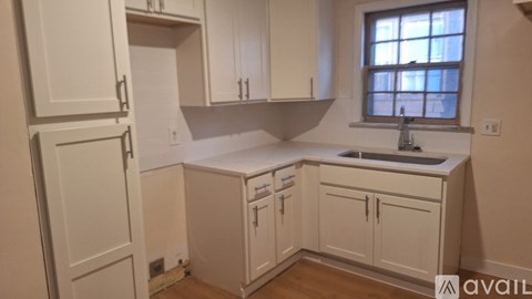 A kitchen with white cabinets and a window.