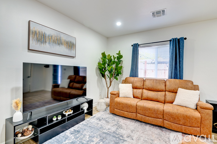 A living room with a brown couch and a painting on the wall.