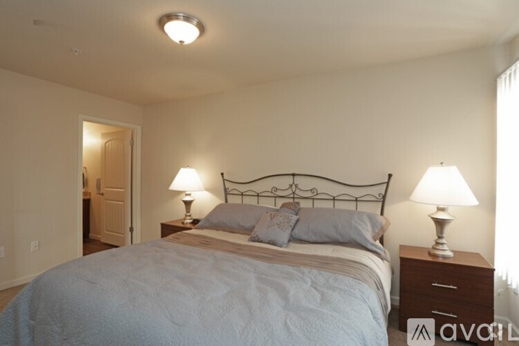 A bedroom with a bed, two lamps, and a nightstand.