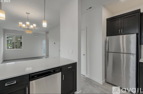 A modern kitchen with a stainless steel refrigerator and black cabinets.
