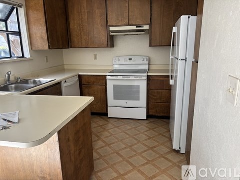 A kitchen with white appliances and brown cabinets.