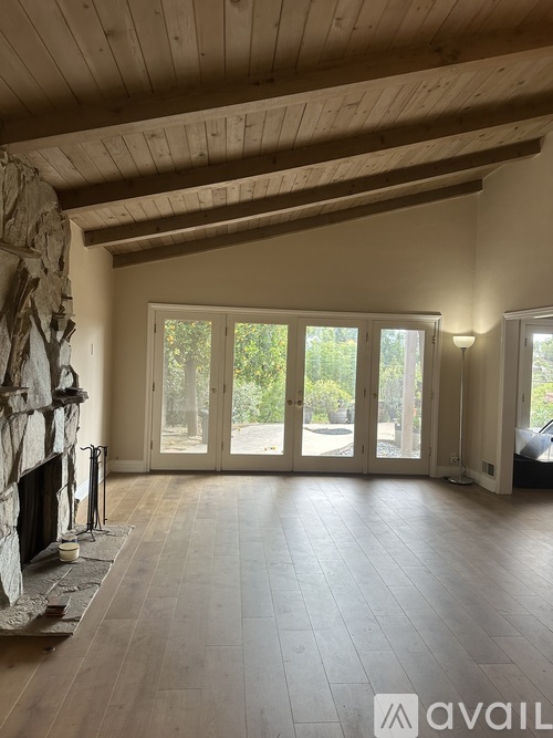 A spacious room with a stone fireplace and large windows.
