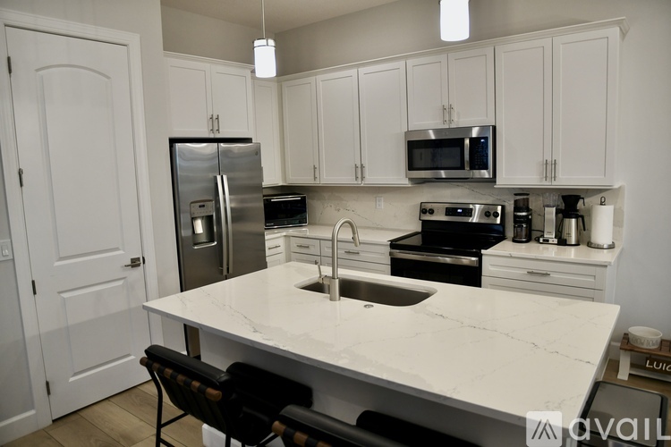 A kitchen with white cabinets and a marble countertop.