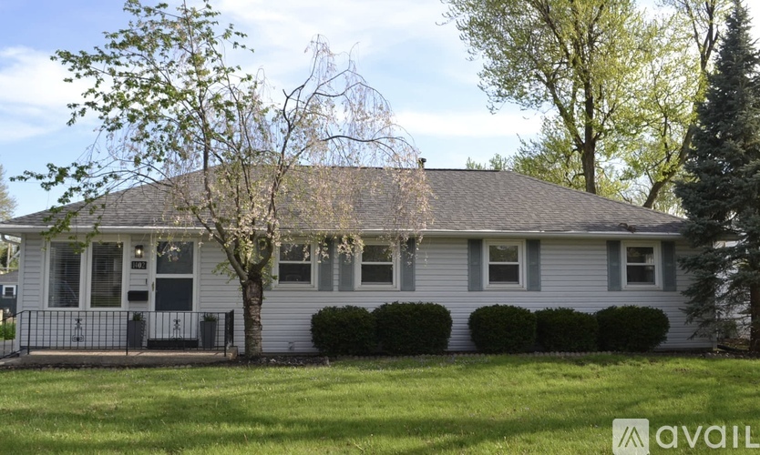 A house with a grey roof and a tree in front.