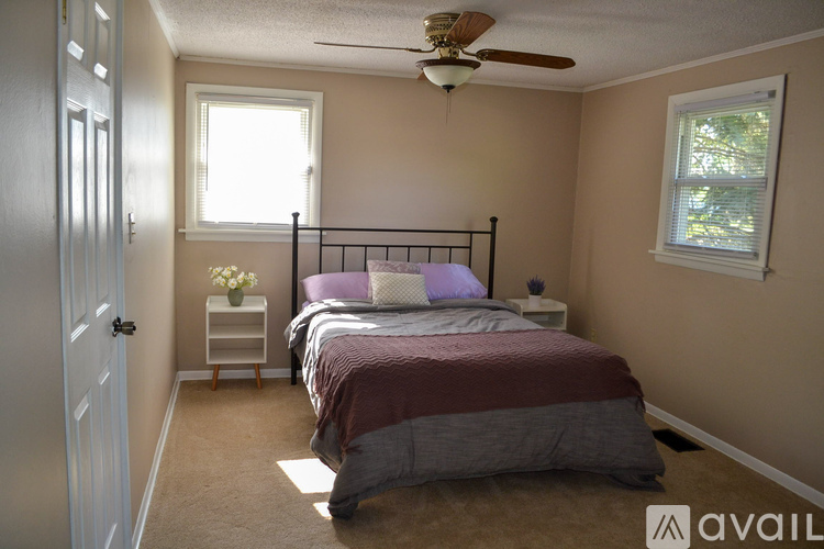 A bedroom with a bed, nightstand, and window.