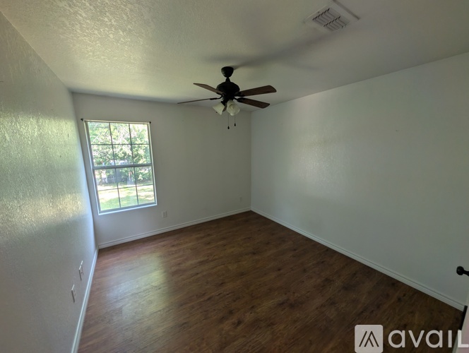 A room with a ceiling fan and wooden flooring.