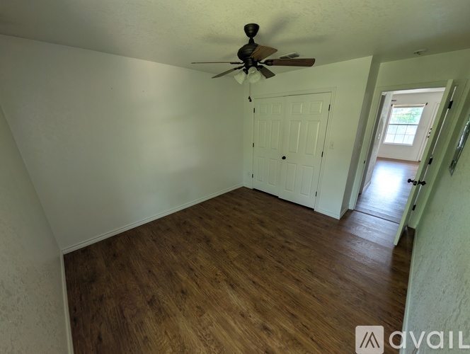 A room with a ceiling fan and wooden flooring.