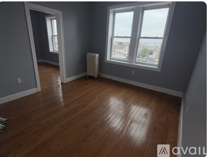 A room with wooden flooring and a window overlooking a balcony.