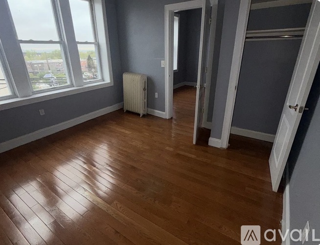 A room with wooden floors and a window overlooking a parking lot.
