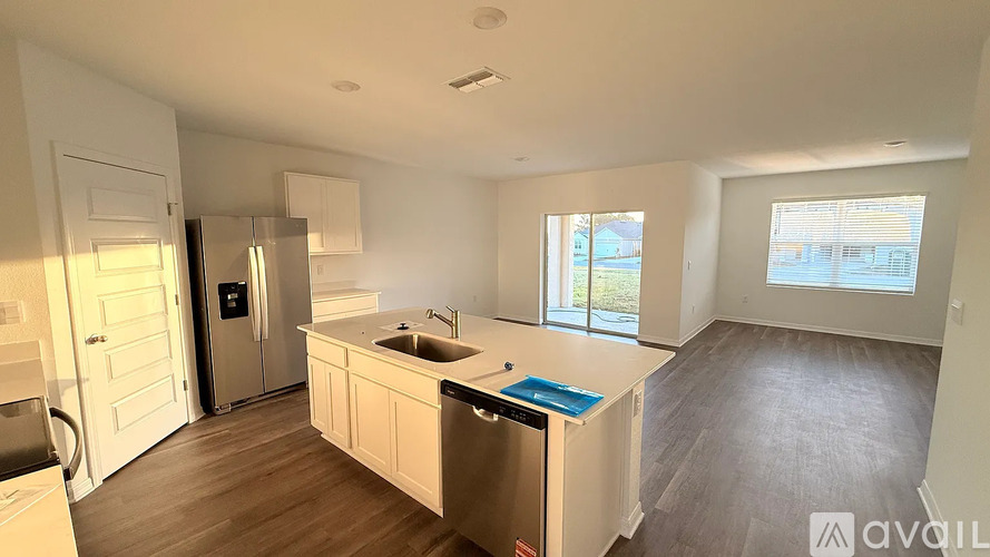 A kitchen with a sink, refrigerator, and a window.