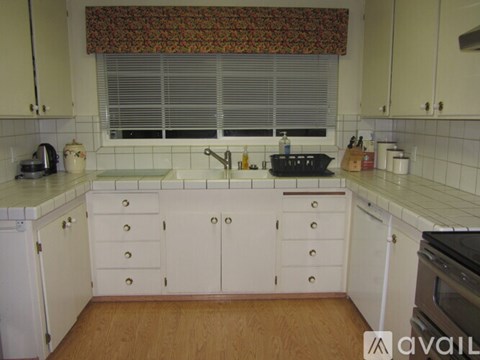 A kitchen with white cabinets and a wooden floor.
