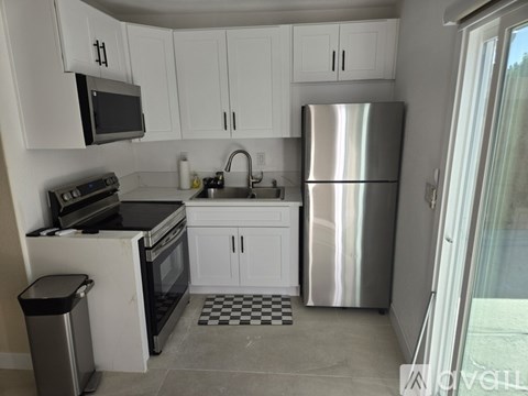 A kitchen with white cabinets and a stainless steel refrigerator.
