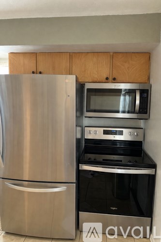 A stainless steel refrigerator and microwave oven are in a kitchen.