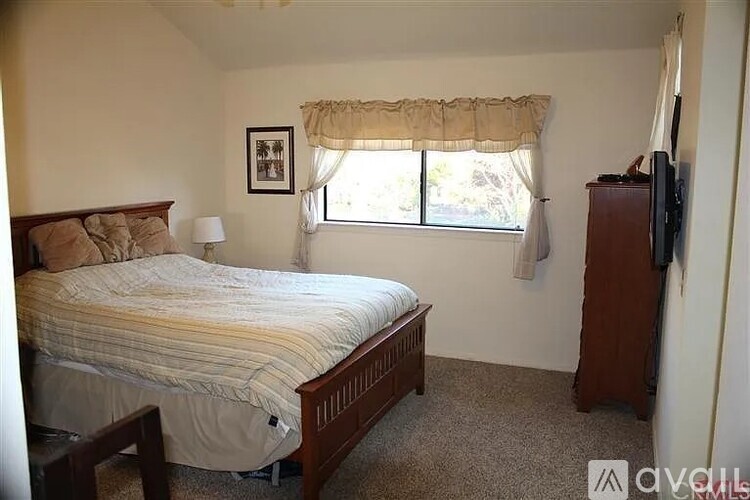 A bedroom with a bed, dresser, and window.