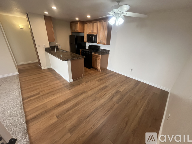 A kitchen with wooden floors and a white ceiling fan.