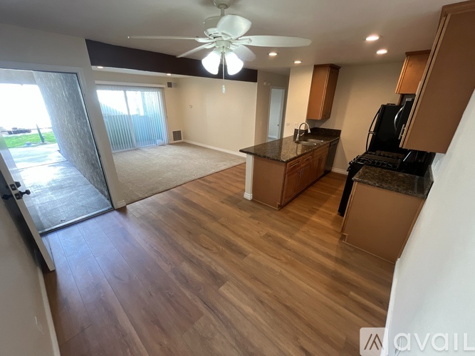 A kitchen with a refrigerator, stove, and a ceiling fan.