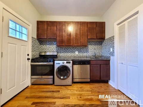 A kitchen with wooden cabinets and a washer and dryer stacked.