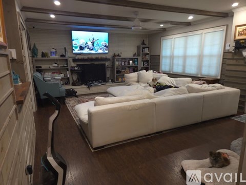 A living room with a white couch and a television on the wall.