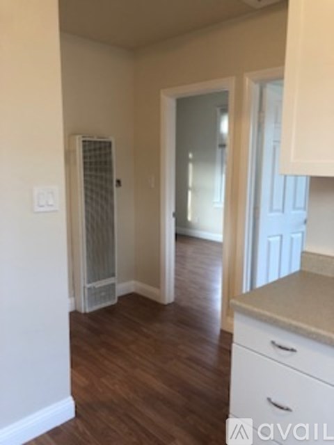 A kitchen with white cabinets and a wooden floor.