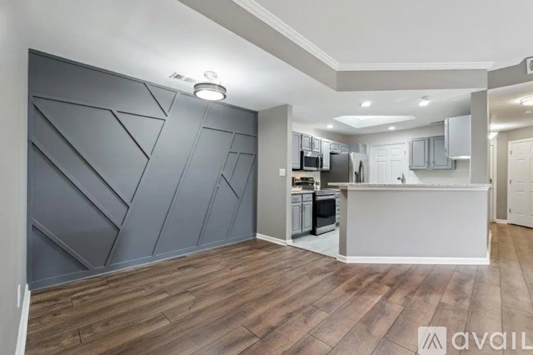 A kitchen area with a white counter and a grey wall with triangular patterns.