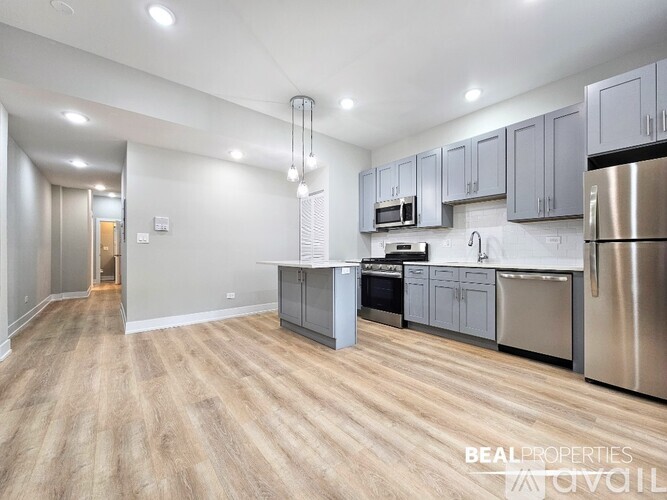 A spacious kitchen with wooden flooring and stainless steel appliances.