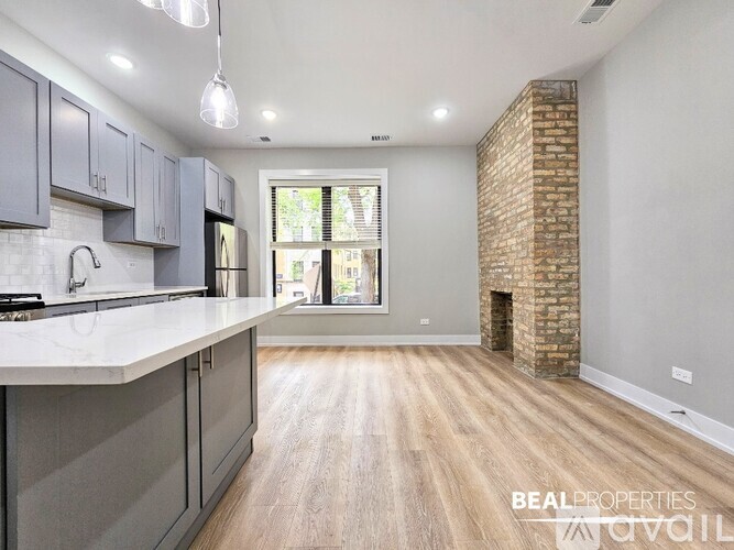 A spacious kitchen with a brick column and wooden floors.