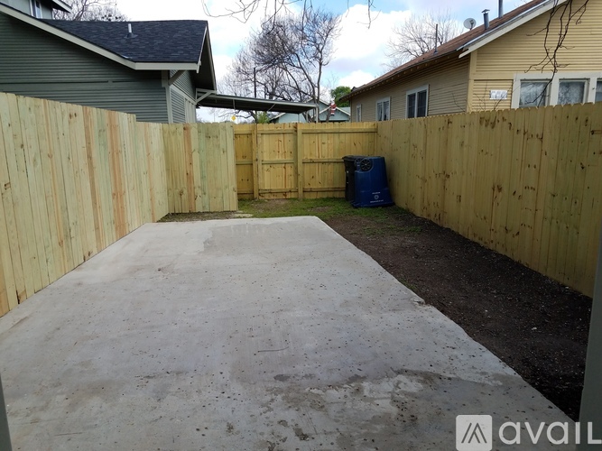 A backyard with a wooden fence and a concrete patio.