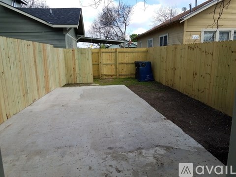 A backyard with a wooden fence and a concrete patio.