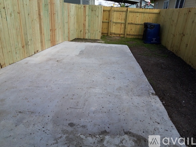 A concrete slab in a backyard surrounded by wooden fences.