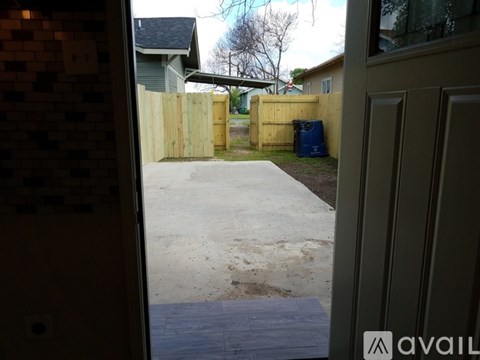 A view from inside a building looking out to a driveway and a fence.