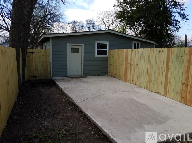 A small blue shed with a white door and a wooden fence.