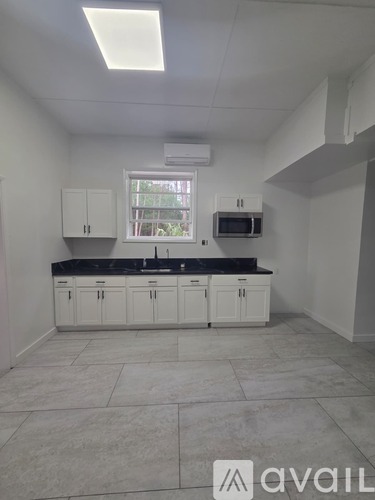 A kitchen with white cabinets and a black countertop.