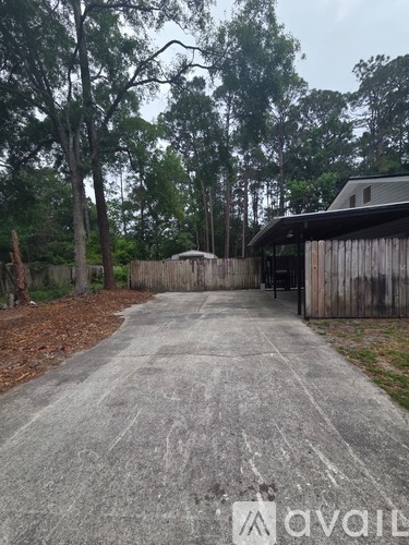 A driveway leads to a wooden building with a metal roof.