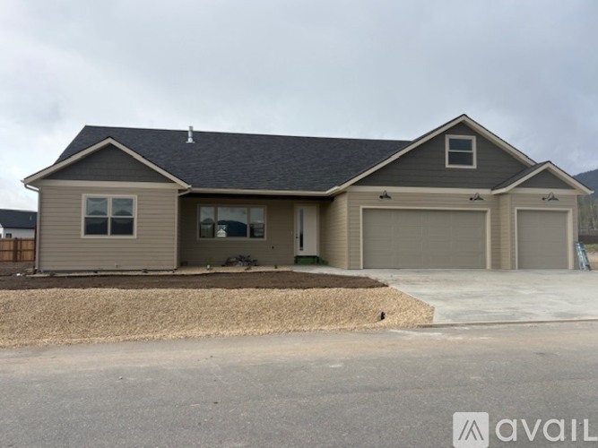 A house with a grey roof and a garage door is available for sale.