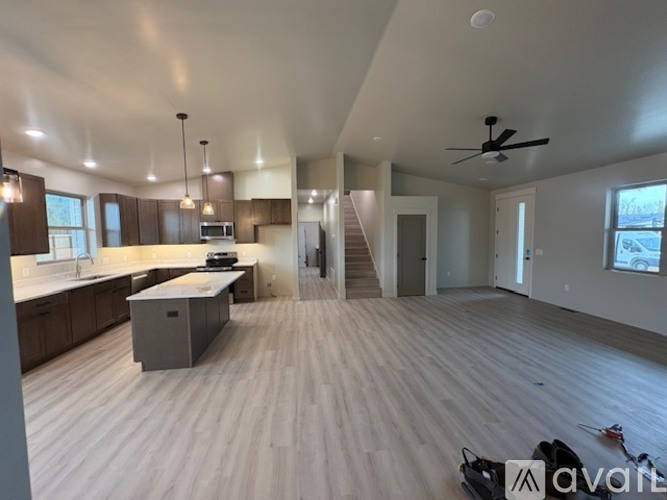 A spacious, empty room with wooden floors and a ceiling fan.
