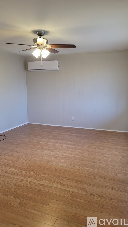 A room with a ceiling fan and wooden flooring.