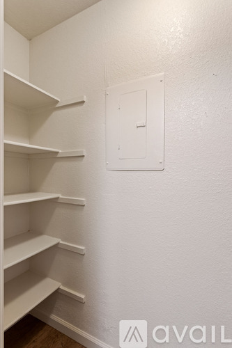 A white wall with a white shelf and a white box on it.