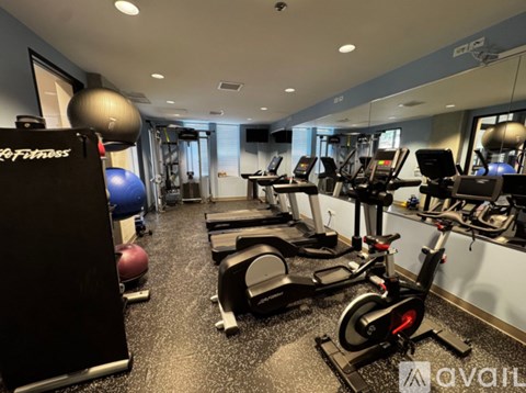 A gym with a variety of equipment including treadmills, stationary bikes, and weight machines.