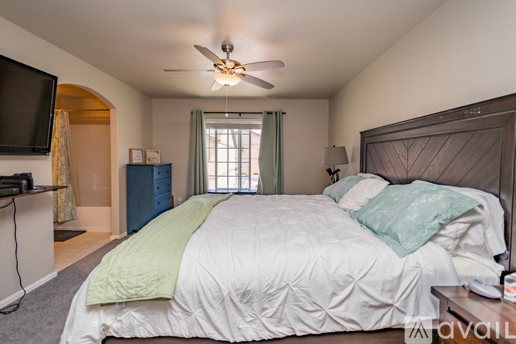 A bedroom with a large bed and a ceiling fan.