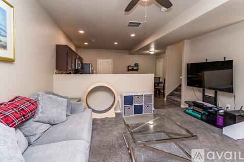 A living room with a grey couch and a glass coffee table.