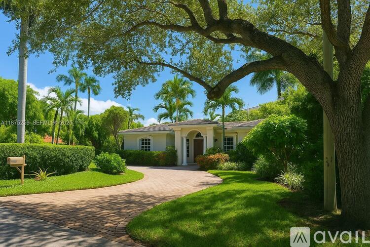 A house with a driveway and a tree in front of it.