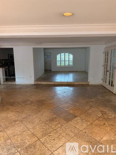 A large empty room with tiled flooring and a window.