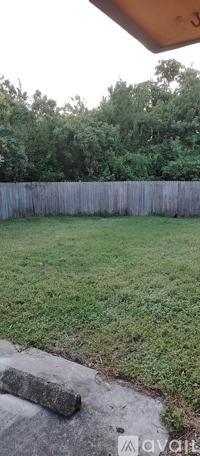 A wooden fence surrounds a grassy yard.
