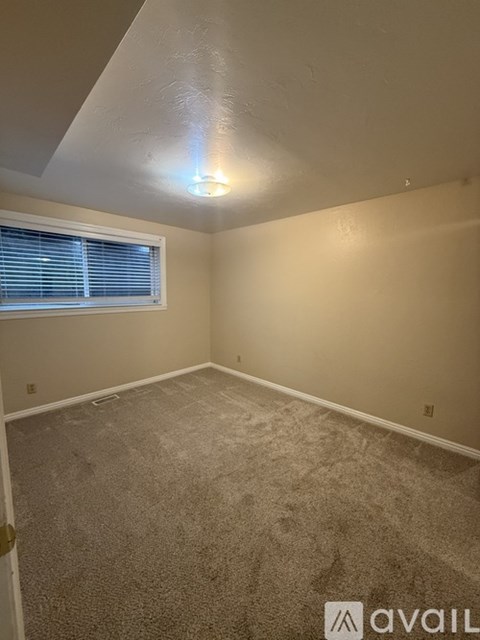 A room with a carpeted floor and a window with blinds.