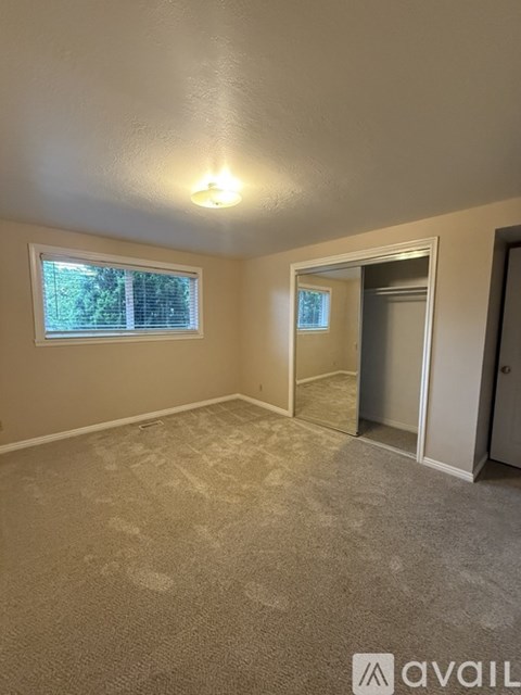 A room with a carpeted floor and a window with blinds.