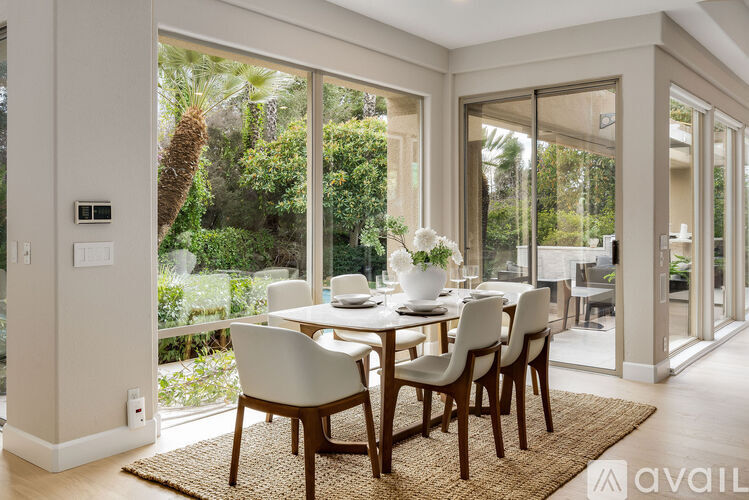 A dining room with a table set for four and a view of the backyard.